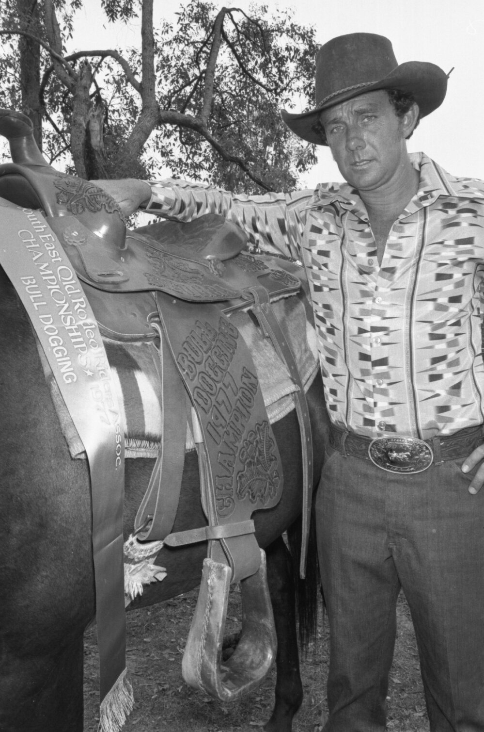 Bulldogging champion posing with his horse, Ipswich, December 1977