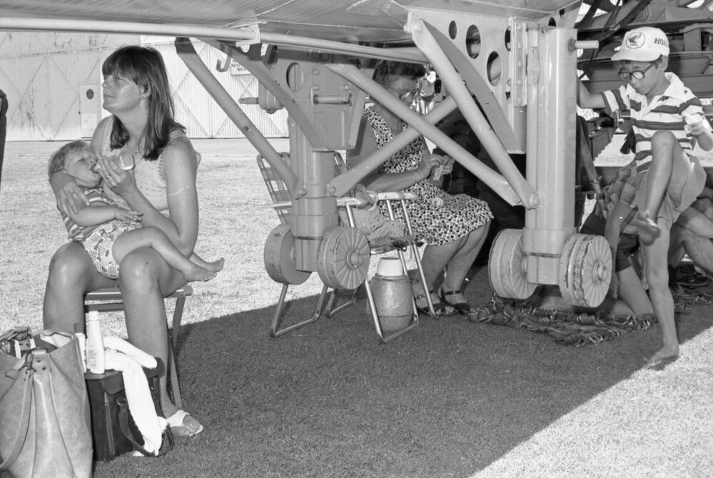 Women and children taking shelter under an aircraft at the RAAF Base, Amberley, December 1977