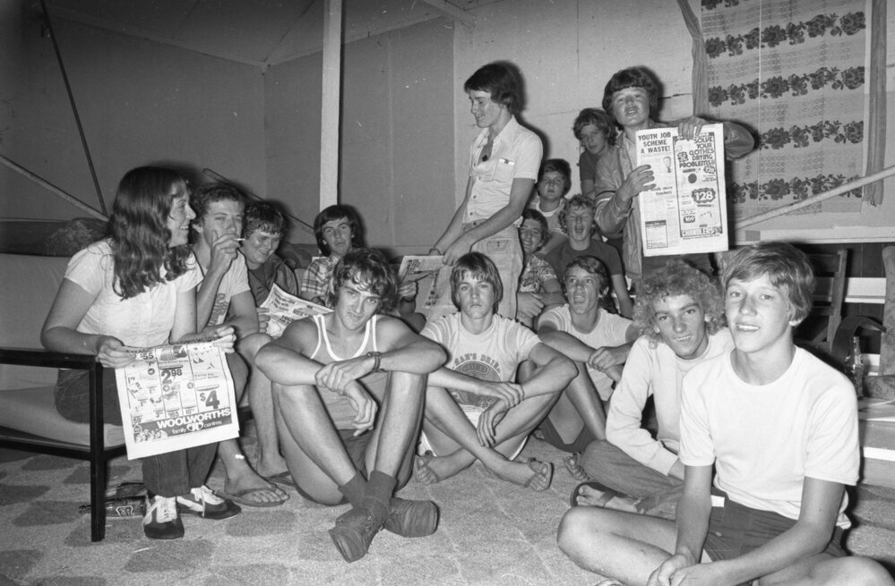 Unidentified group of teens gathered in room, reading newspapers and referring to Youth Job Scheme, Ipswich, February 1978