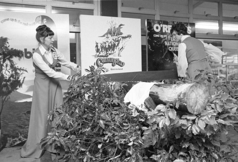 Two unidentified women in uniform performing a demonstration of a long saw on a log in Booval Fair, Booval, Ipswich, February 1978