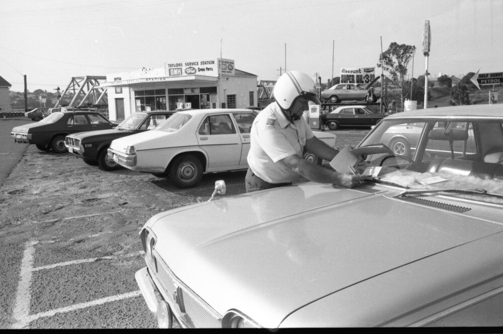 Norm Fletcher writing ticket on car at Taylor's Service Station, Ipswich, February 1978