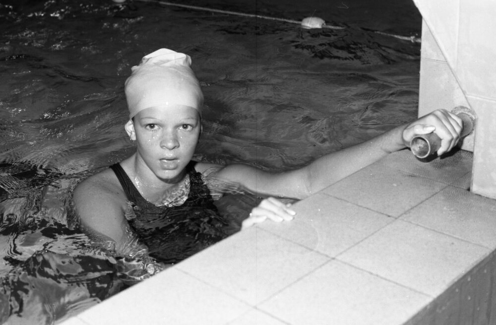 Unidentified swimmer wearing a swimming cap at a starting block in a pool, Ipswich, Queensland, February 1978