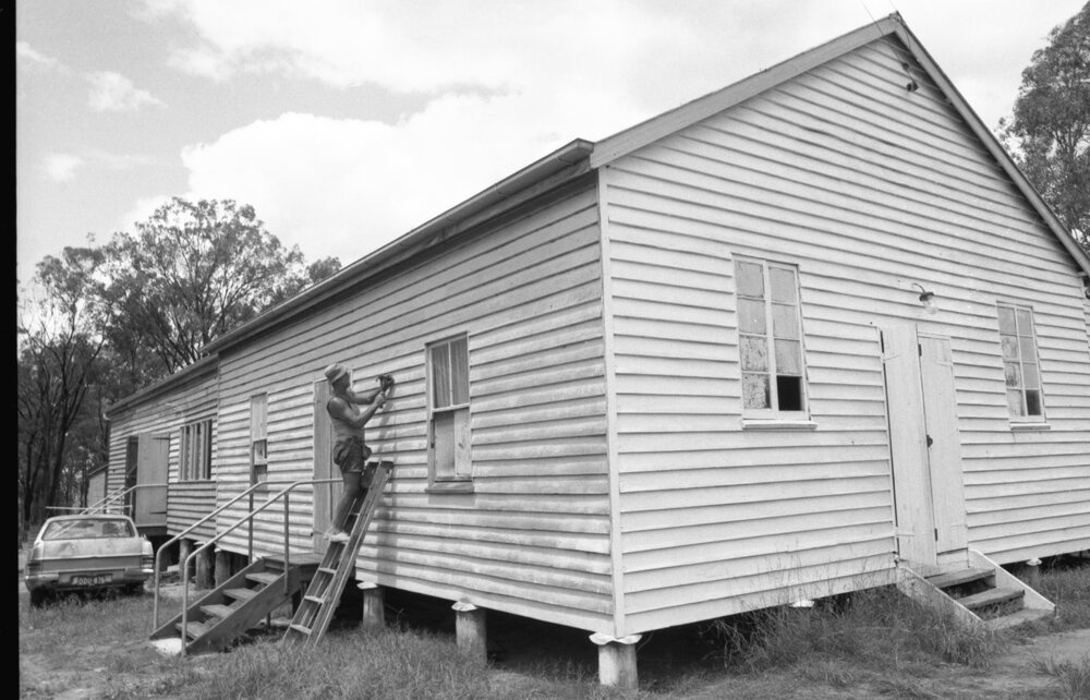 Man using hammer on exterior of Coominya Public Hall, Coominya, 15th February 1978