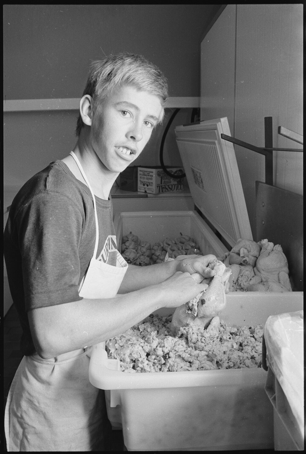Unidentified teenager shredding chicken pieces by hand, Ipswich, July 1985