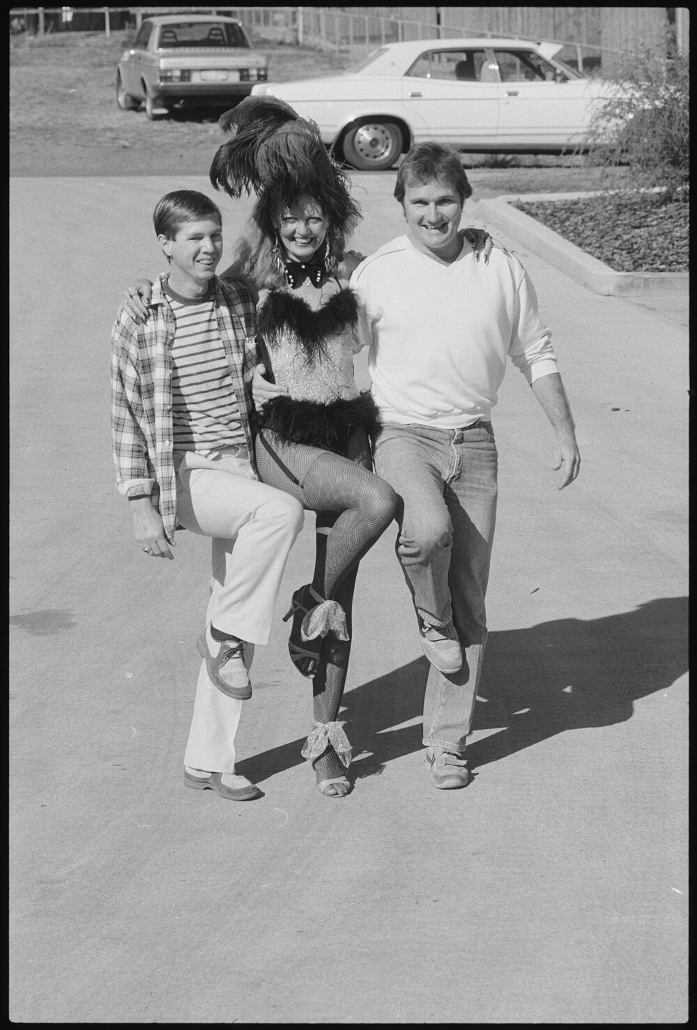 Unidentified Burlesque dancer with two men in a car park, Ipswich, July 1985