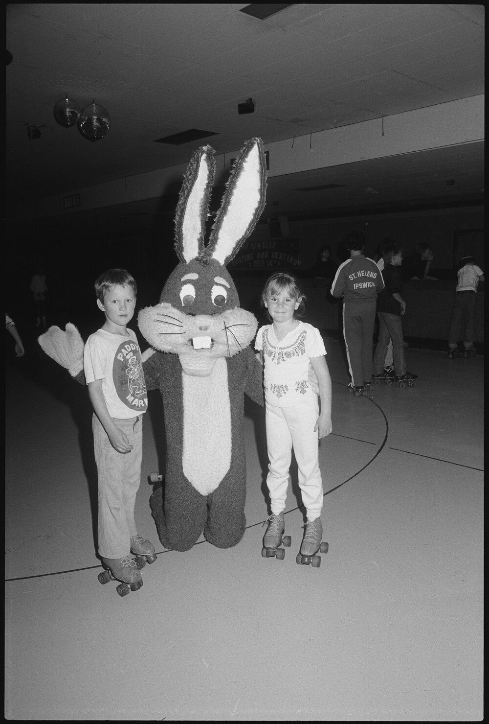 Two unidentified children with a bugs bunny mascot at a roller skating rink, Ipswich, July 1985