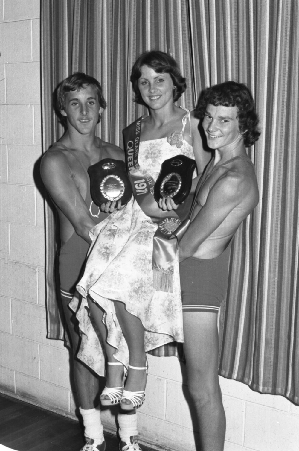 Unidentified wrestlers holding the 1977 Miss Queensland Amateur Wrestling Queen, Ipswich, November 1977