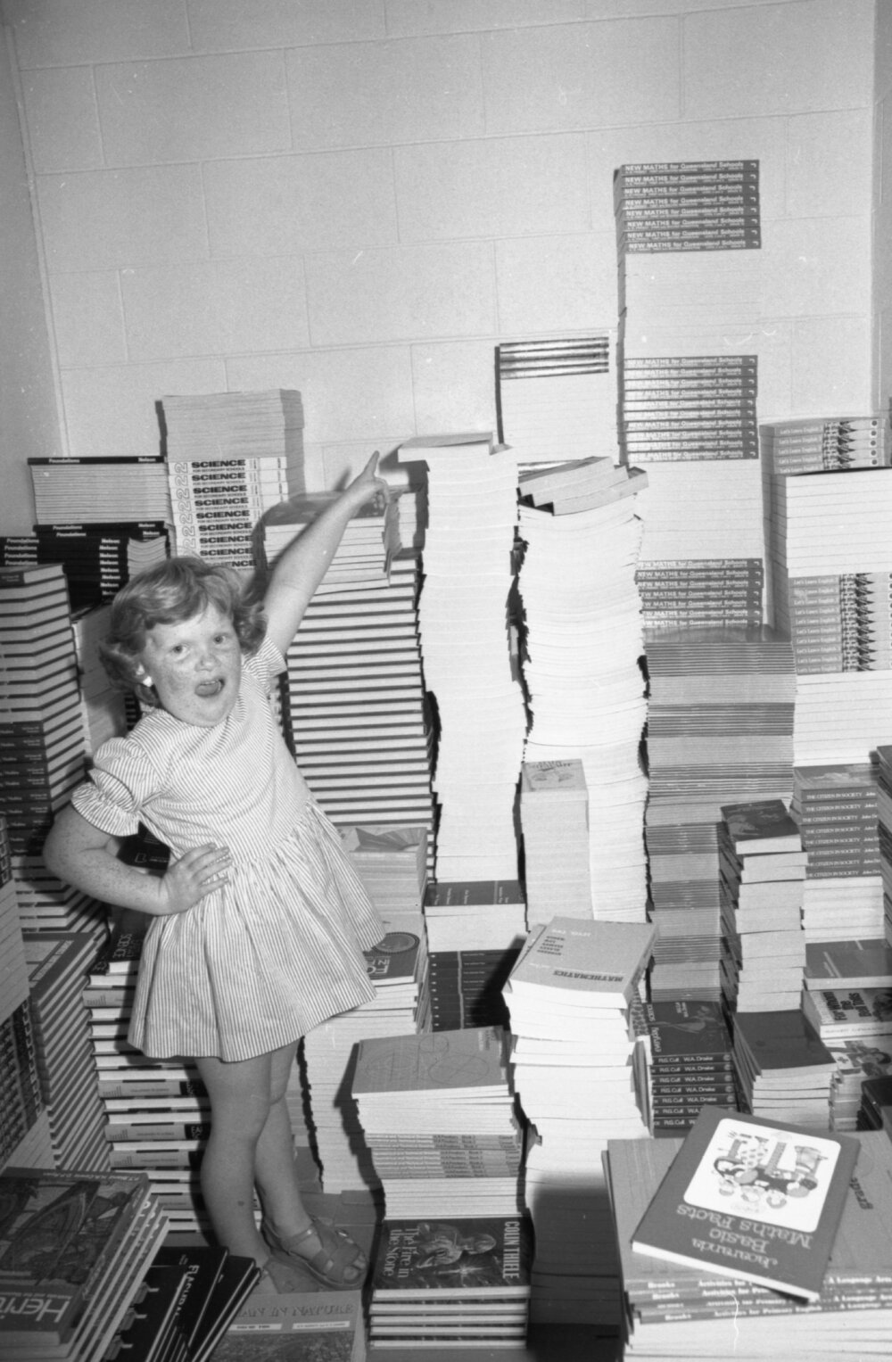 Little girl posing with stacks of books, thought to be Brodie's Bookstore, Ipswich, January 1978