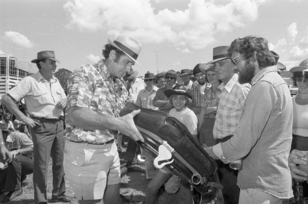 Unidentified men inspect horse collar for sale at an unidentified horse event, Ipswich, February 1978