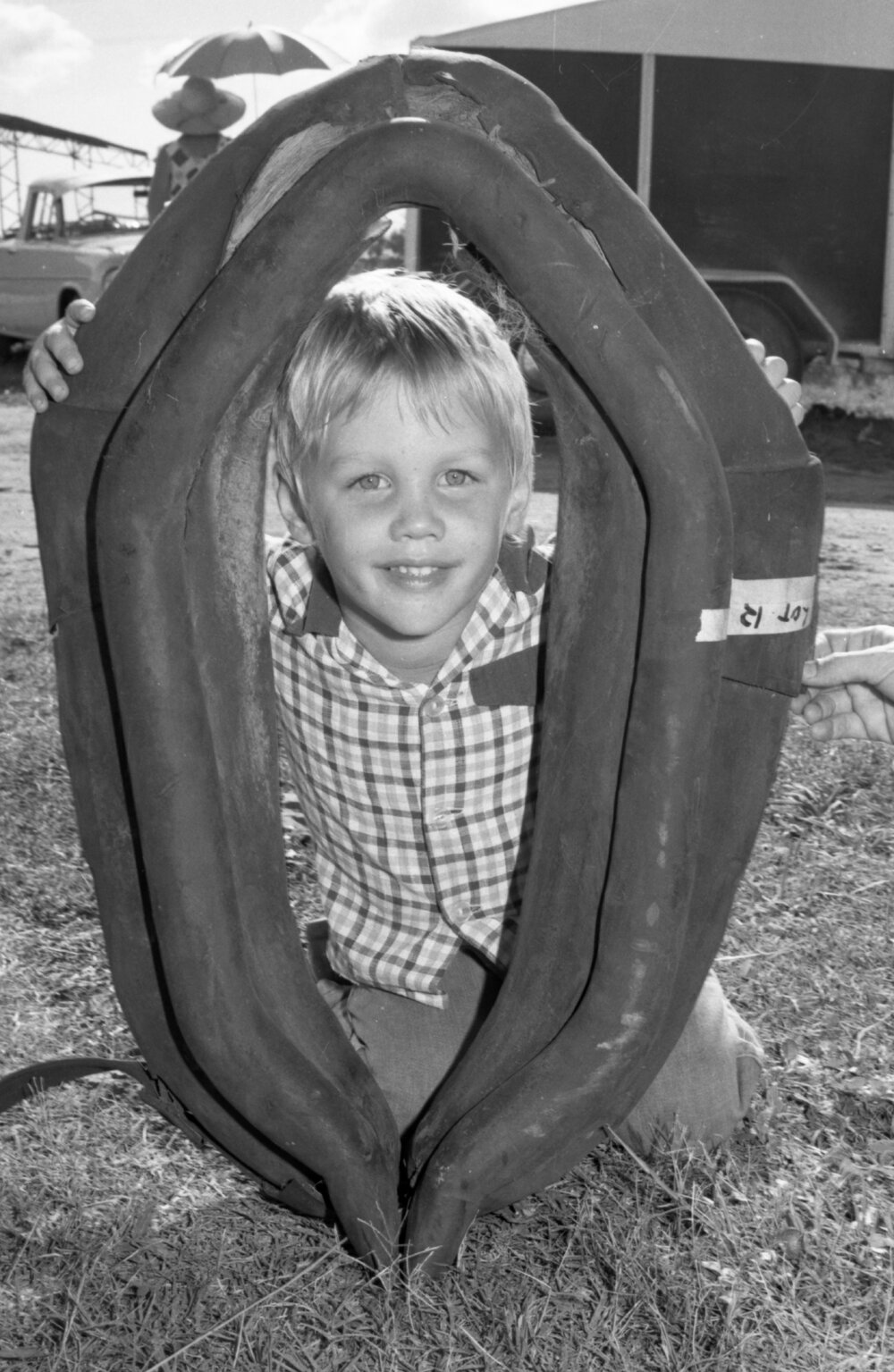 Unidentified little boy smiling with a horse collar for sale at an unidentified horse event, Ipswich, February 1978