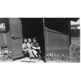 Three servicewomen posing in front of a small fibro shed at the Amberley Airbase, 1943