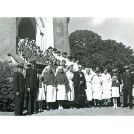 Heather Kennedy and Betty Pedersen grouped with  nurses and ambulance officers on the stairs of St Stephen's Presbyterian Church following Sunday church services, Ipswich, 10 May 1953