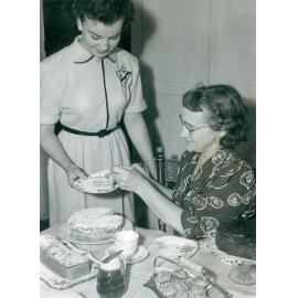 Mrs Edwin Evans (Queenie) gives a slice of cake to her daughter at Goodna, 1953