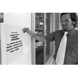 Unidentified man standing in front of a political poster, Ipswich, December 1977