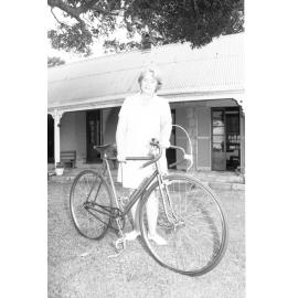 Mrs Wass standing with an antique bicycle outside Wolston House, Wacol, Queensland, January 1978