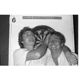 Two men with darts board, Ipswich, January 1978