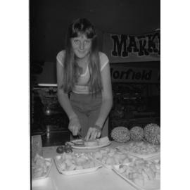 Unidentified woman preparing pineapple outside Morfield Meats in Booval Fair, Booval, Ipswich, February 1978