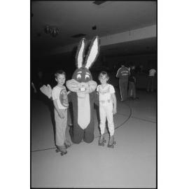 Two unidentified children with a bugs bunny mascot at a roller skating rink, Ipswich, July 1985