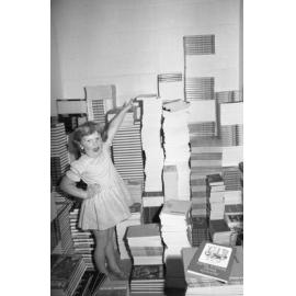 Little girl posing with stacks of books, thought to be Brodie's Bookstore, Ipswich, January 1978