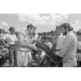 Unidentified men inspect horse collar for sale at an unidentified horse event, Ipswich, February 1978