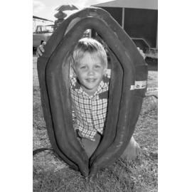 Unidentified little boy smiling with a horse collar for sale at an unidentified horse event, Ipswich, February 1978