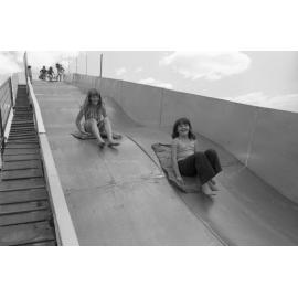Kids on a slide at Goodna State School Fete, Goodna, October 1977