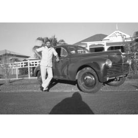 Man standing outside timber house with Peugeot 203 car, Ipswich, February 1978