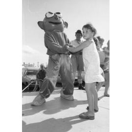 Girl dancing with mascot on stage at the Lions Carnival, Ipswich, December 1979