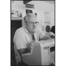 Unidentified man working as a bartender standing in front of a cash register, Ipswich, January 1986