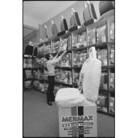 Unidentified man looking at different car seat covers in an auto parts and accessories store, Ipswich, July 1985