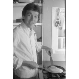Unidentified man cooking pancakes, Ipswich, February 1985