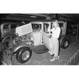 Unidentified woman standing beside a vintage 1928 Ford Sedan car at a Hot Rod Show, Ipswich, August 1980