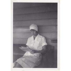 Nurse Judy Kemp reading on bench, Ipswich, 1950s