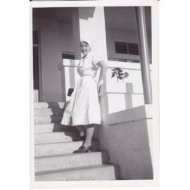 Nurse Gloria Young (nee Batzloff) standing at the steps of Trumpy House, Ipswich General Hospital, Ipswich, 1950s