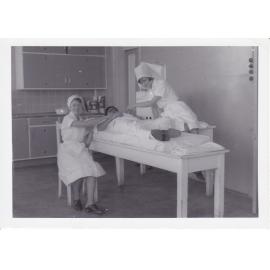 Nurses D. Pocock, P. Devereaux and Dr Chong Wah in treatment room, Ipswich General Hospital, 1950s 