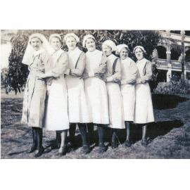 Registered Nurse and 6 Students in front of Original Building, 1930s