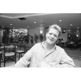 Man sitting in the dining area outside the bottle shop at the opening of Ipswich City Square, Ipswich, August 1987 