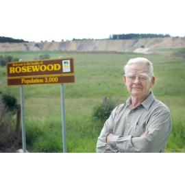 Arnold Rieck, standing beside the "Welcome to Rosewood" sign, Rosewood, Ipswich, March 2003