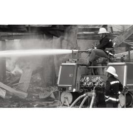 Firefighters hosing down the remains of the Reid's store following the fire, Ipswich, August 1985