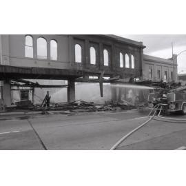 Firefighters hosing down the remains of the Reid's store following the fire, Ipswich, August 1985