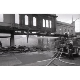 Firefighters hosing down the remains of the Reid's store following the fire, Ipswich, August 1985
