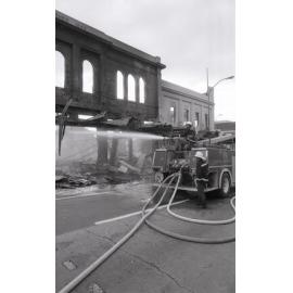 Firefighters hosing down the remains of the Reid's store following the fire, Ipswich, August 1985