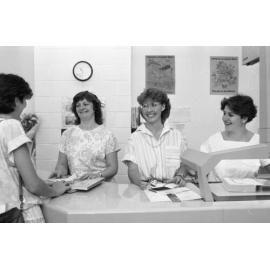Unidentified staff members at Redbank Plaza Library helping a patron check out a book, Redbank, September 1985