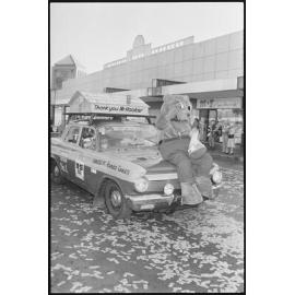 L.J. Hooker real estate bear mascot riding on the bonnet of the company's sponsored vehicle as part of the Variety Bash parade, Brisbane Street, Ipswich, 5th August 1994 