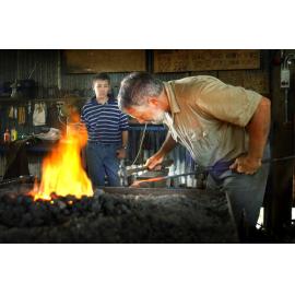 Blacksmith Alan Morris works on a piece of hot steel as his son Jeffery looks on, Ipswich, 18th January 2005 