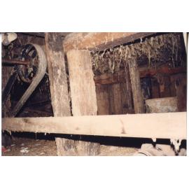 Hand hewn logs and old machine belt pulleys in the cellar of Risson's Produce