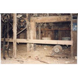 Hand hewn logs and old machine belt pulleys in the cellar of Risson's Produce