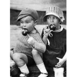 Ken Booth, 2, with sister Wray Duncanson, 4, (nee booth) eating toffee apples at the Ipswich Show, Ipswich, 1934