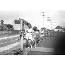 Unidentified woman, dressed for tennis, in front yard of home on Brisbane Street, West Ipswich, 1950s