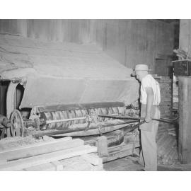 Worker using sawmill machinery at Kruger Sawmill, Byrne Street, Bundamba, Ipswich, 1959